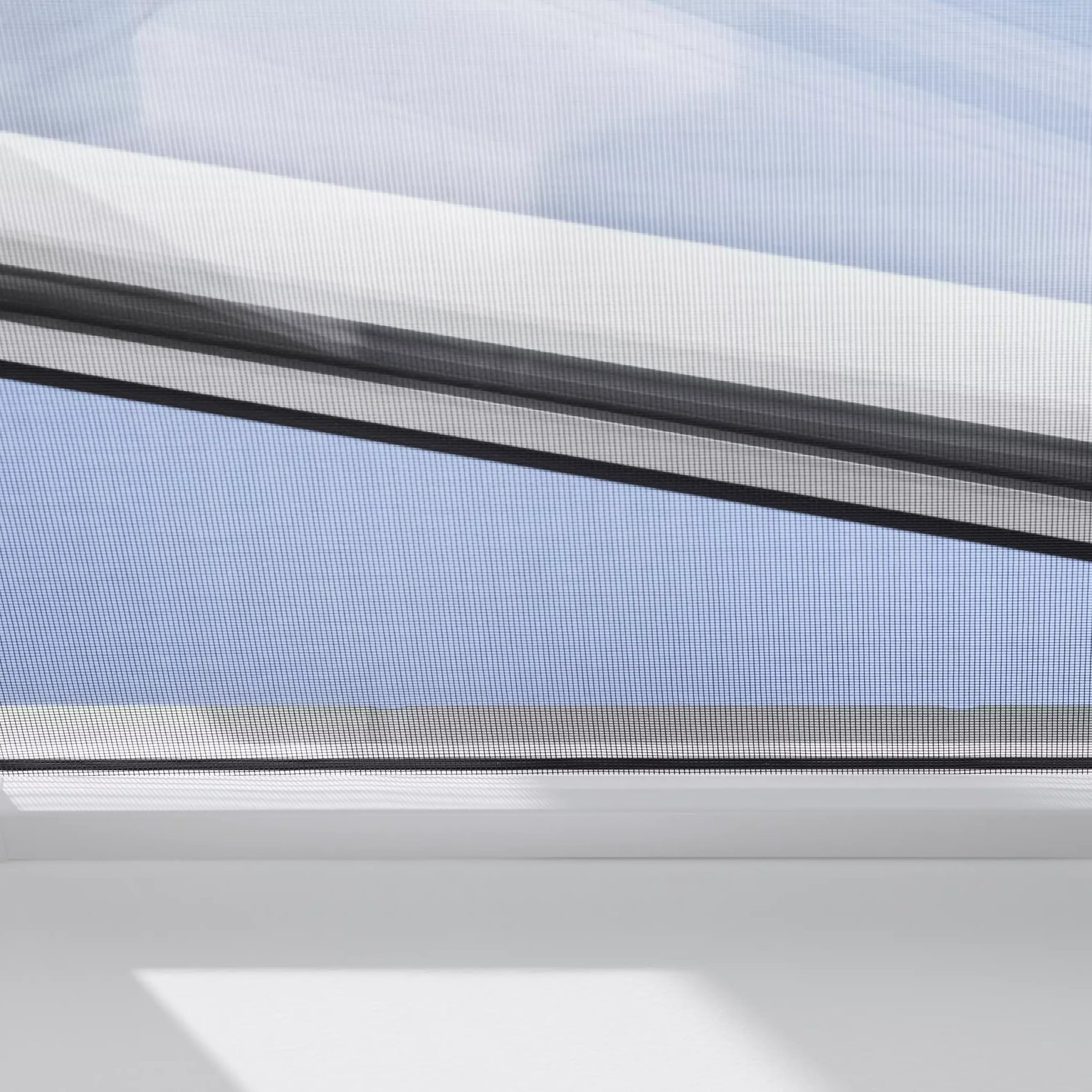 Open VELUX roof window with clear blue sky visible.