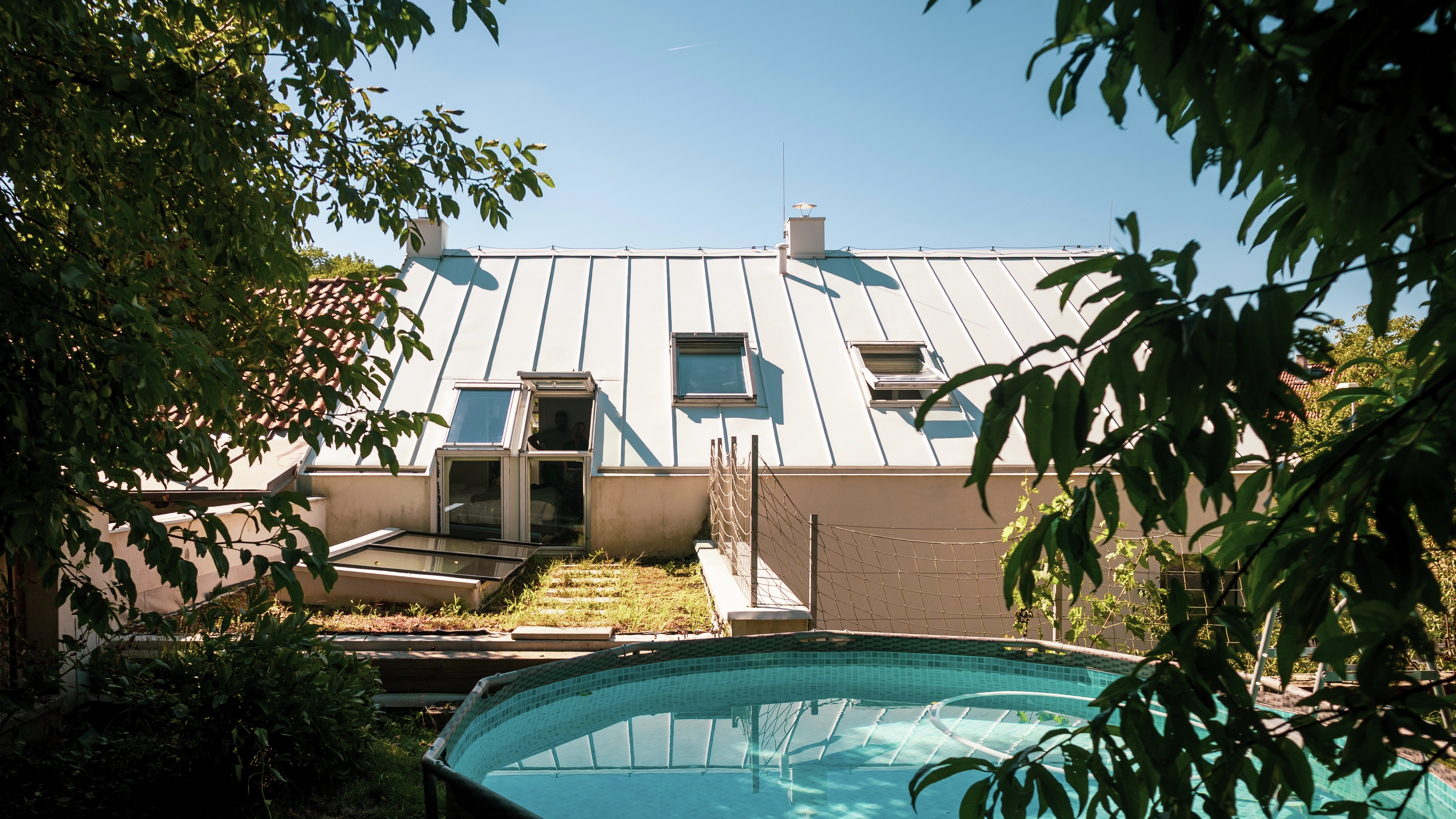 House with metal roof, VELUX windows, garden, and pool.