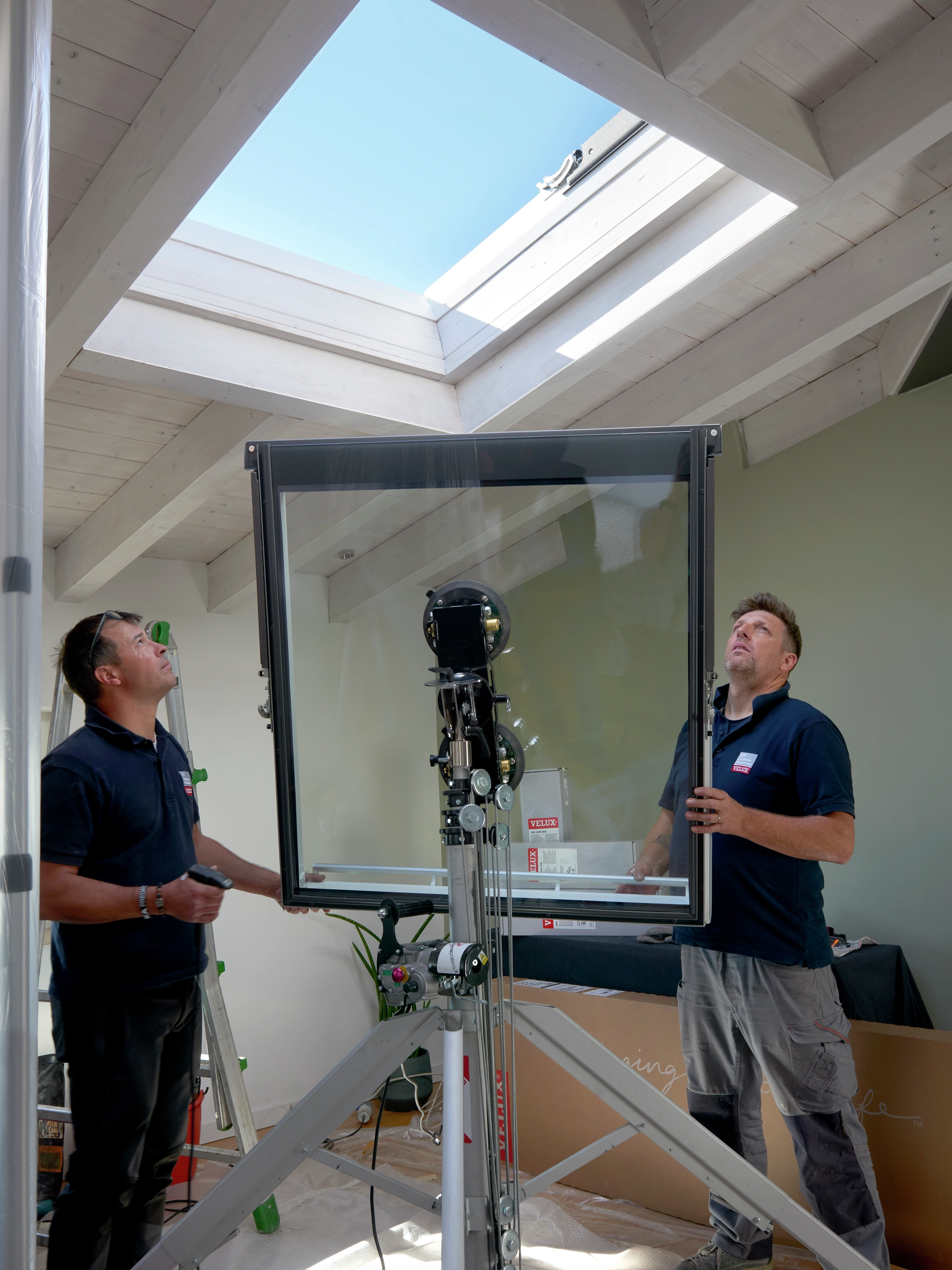VELUX roof window installation in a room with sloped ceiling and wooden beams.