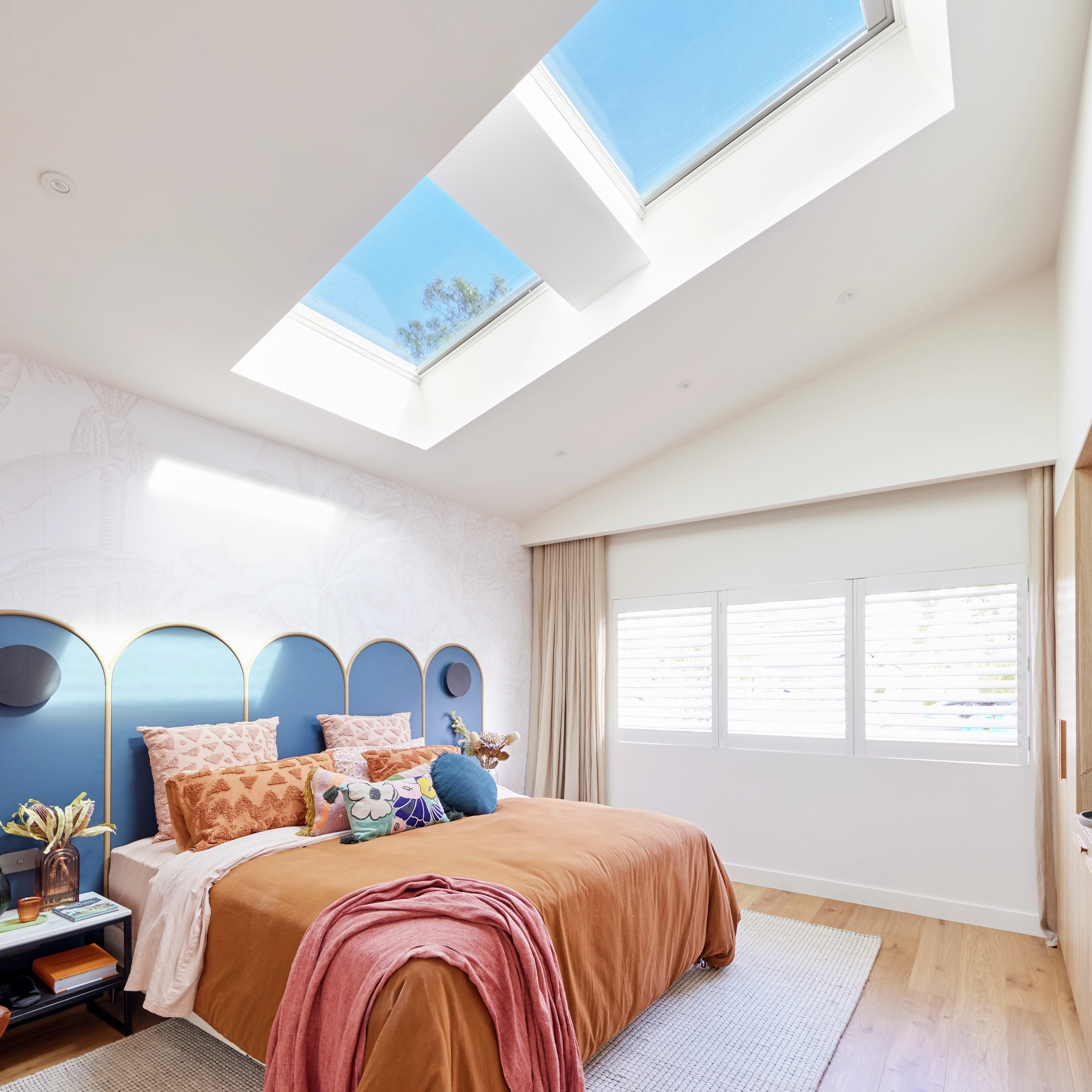 Bedroom with sloped ceiling and VELUX roof windows, bright and airy.