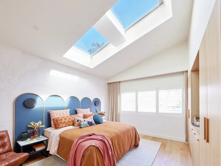 Bedroom with sloped ceiling and VELUX roof windows, bright and airy.