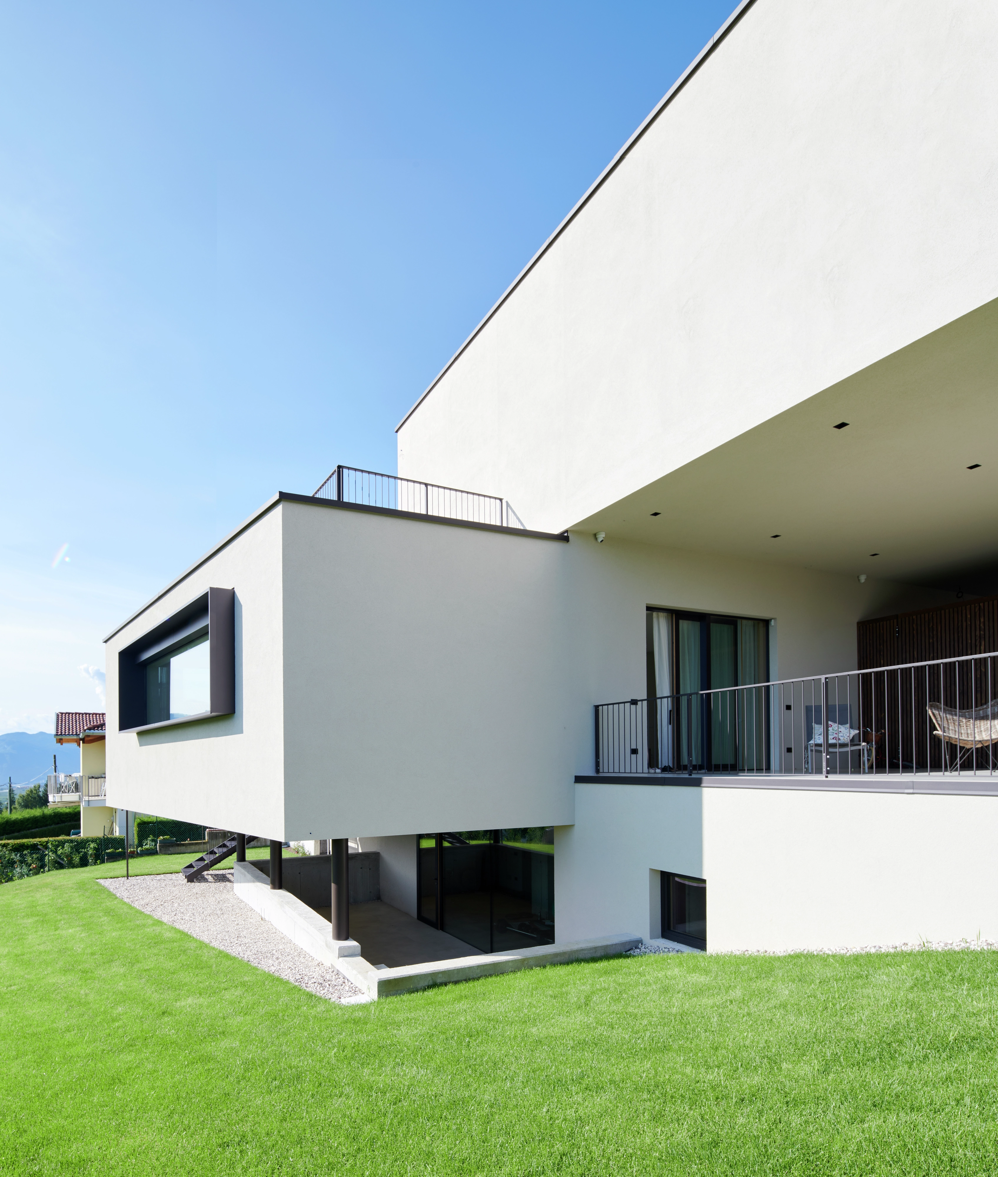 Maison individuelle moderne avec de grandes fenêtres et un toit plat face à un ciel bleu.