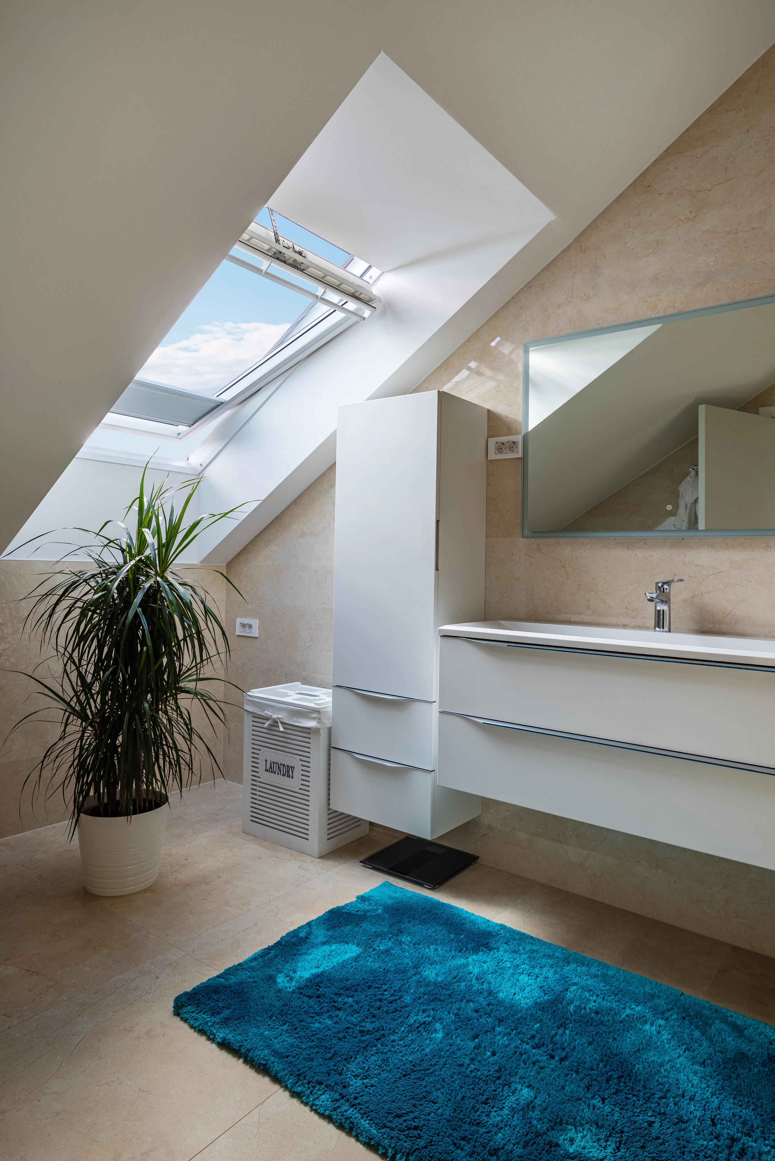 Bēniņu vannas istaba ar slīpiem griestiem un atvērtu VELUX jumta logu.