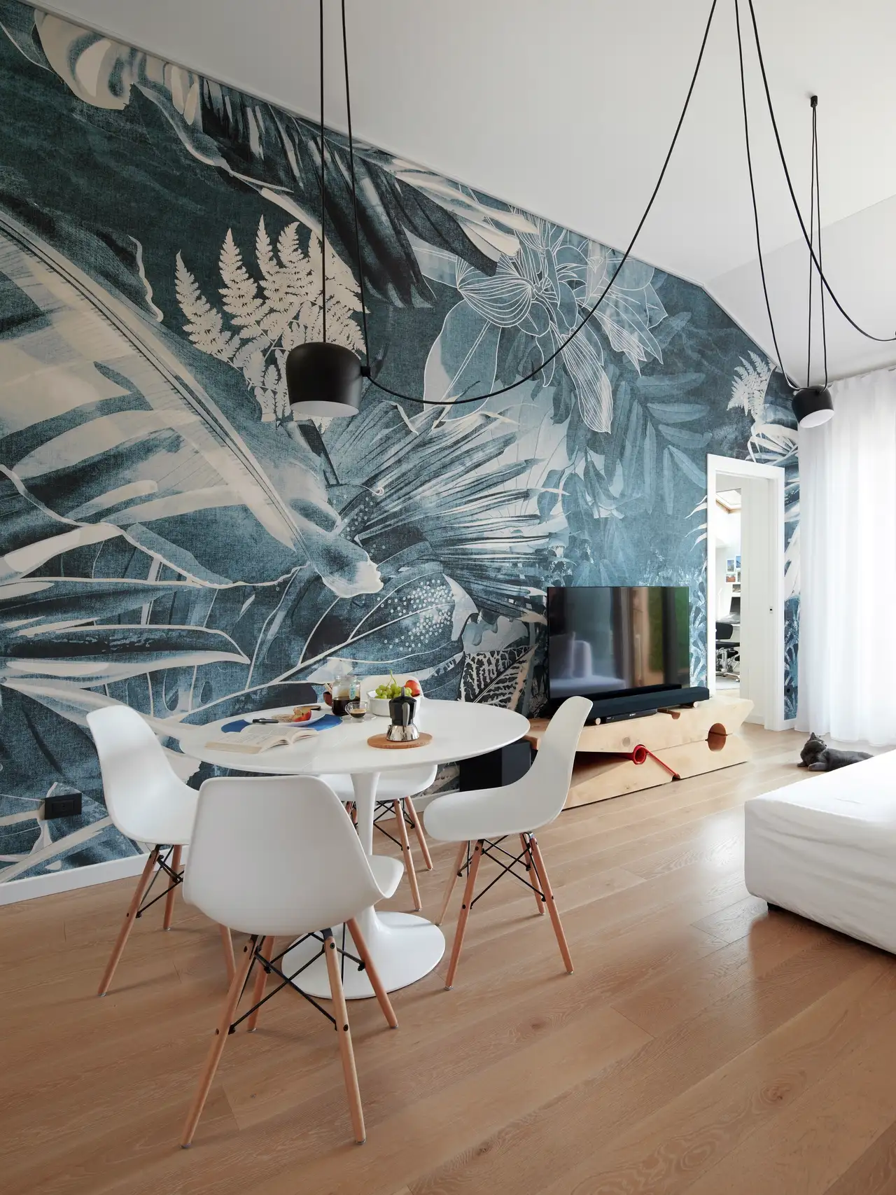 Coin repas et salon sous combles avec un pan de mur habillé de papier peint floral