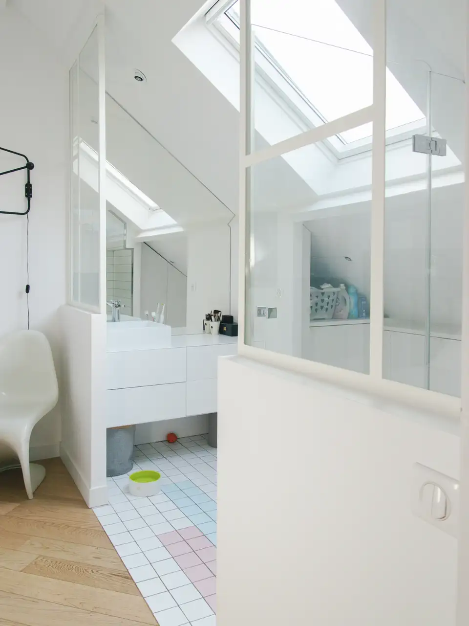 Salle de bain mansardée avec baignoire sous une grande fenêtre de toit.