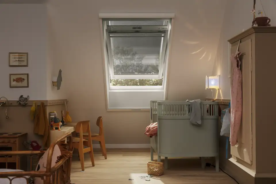 In een kinderkamer stroomt het daglicht  binnen via een VELUX dakraam, zacht gefilterd door een buitenzonwering.