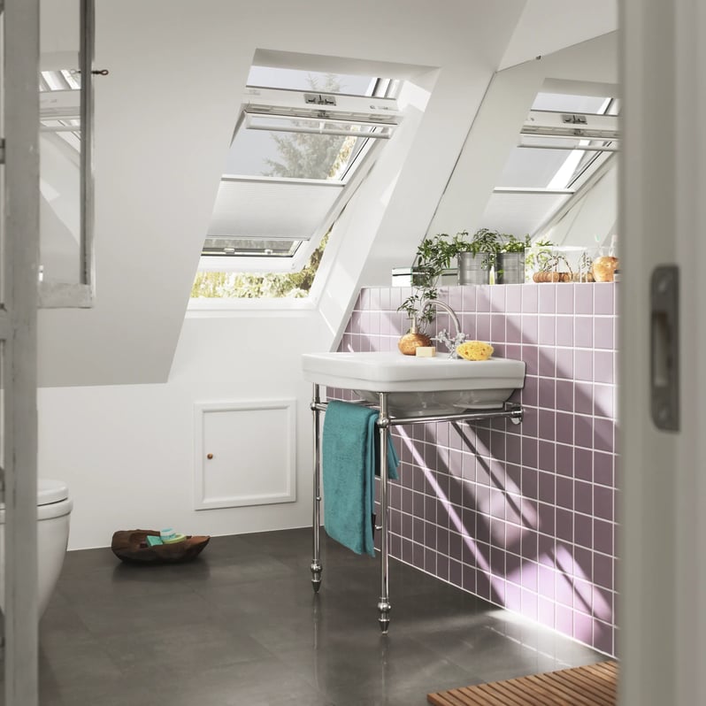 Attic bathroom with sloped ceiling and VELUX roof windows, purple tiles.