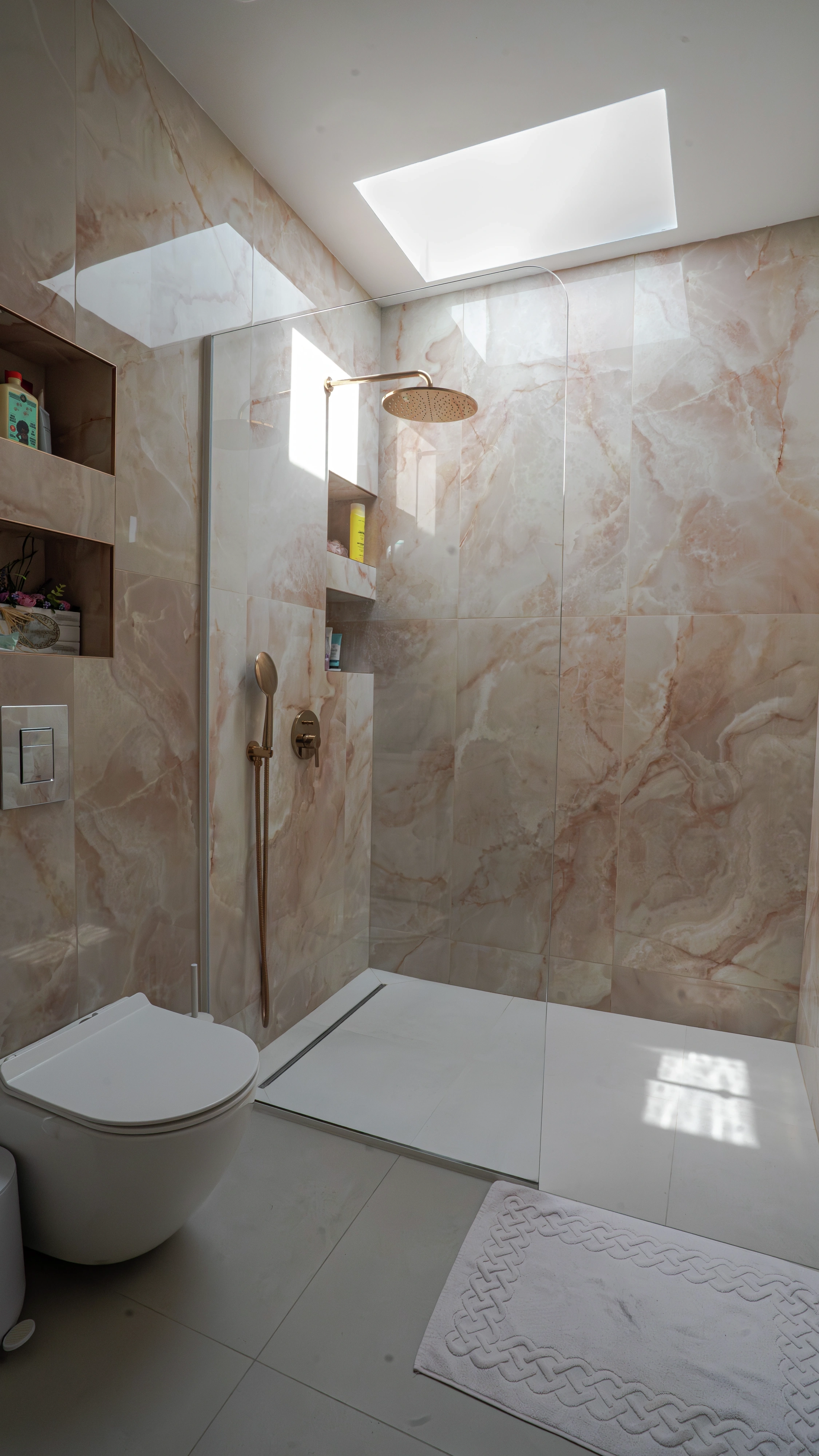 Modern marble bathroom with walk-in shower lit by VELUX flat roof window.