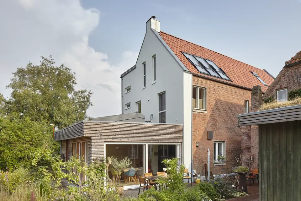"Maison moderne avec fenêtres de toit VELUX et toit en tuiles rouges, entourée de verdure."