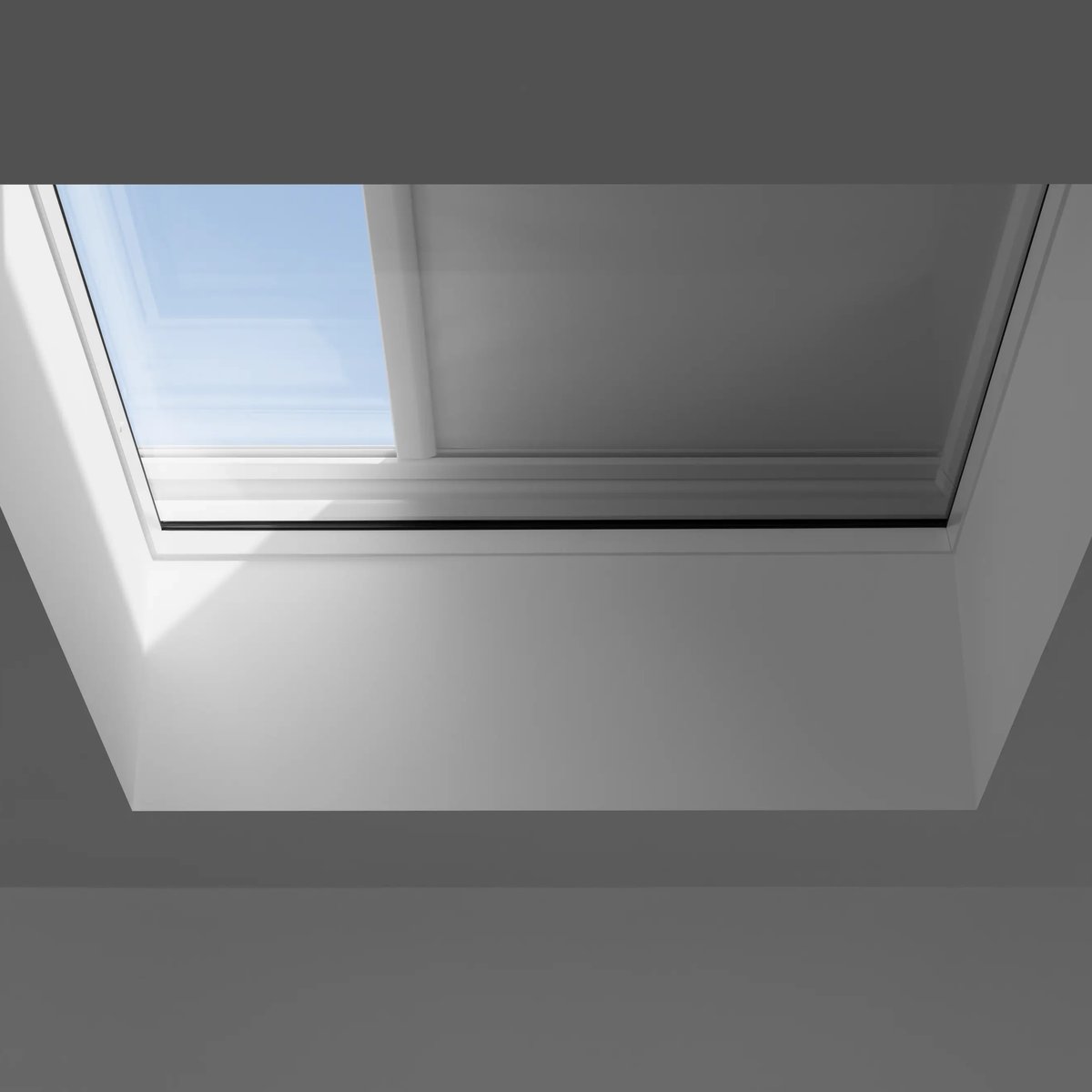 Closed VELUX roof window with clear view of blue sky.