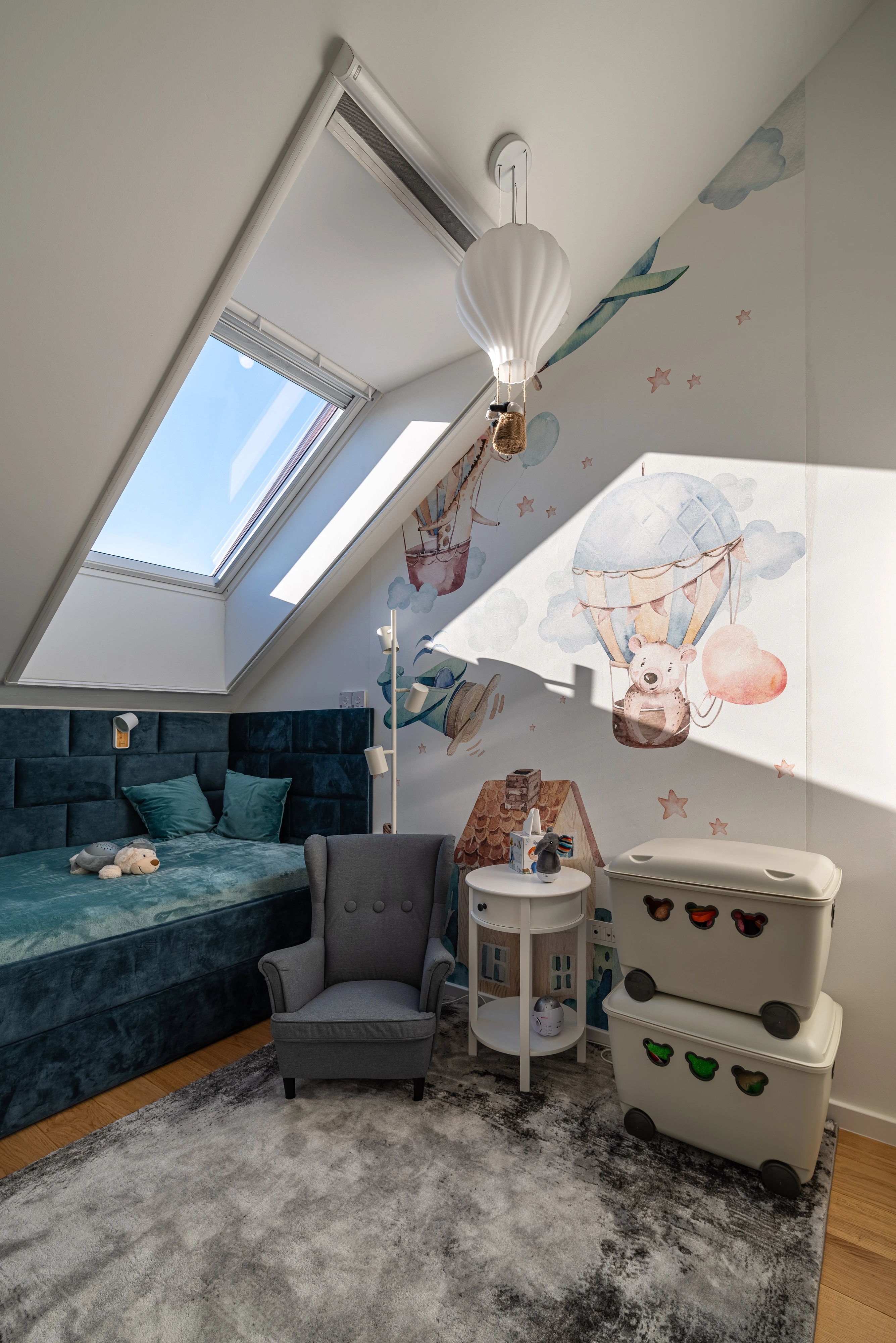 Bērnu bēniņu istaba ar slīpiem griestiem un VELUX jumta logu, rotaļīgs dekors.