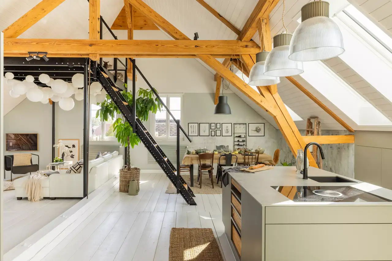 Loft moderne et industriel sous les combles, avec escalier en métal et mezzanine.