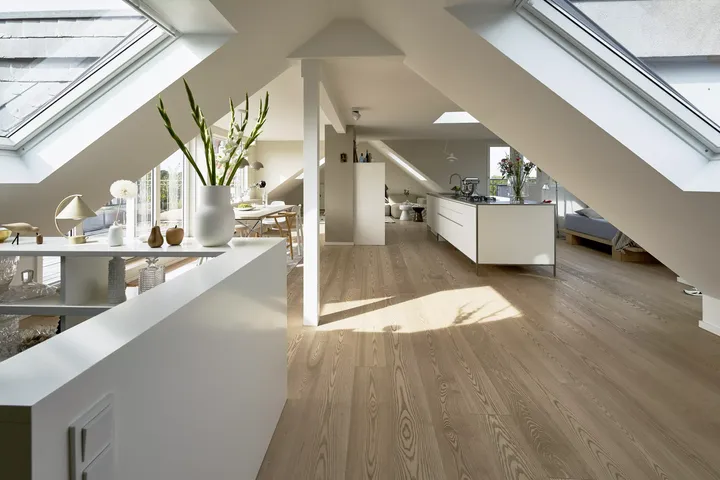 Moderne Dachbodenküche mit VELUX Dachflächenfenstern und hölzernen Böden.