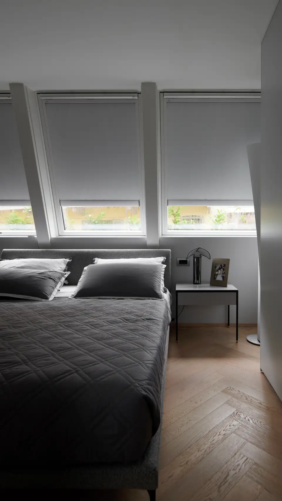 chambre avec lit sous deux fenêtres de toit VELUX équipées de stores occultants