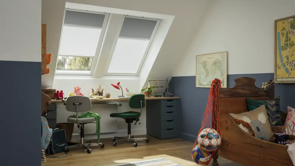 Attic kids room with sloped ceiling and VELUX roof windows, colorful decor.