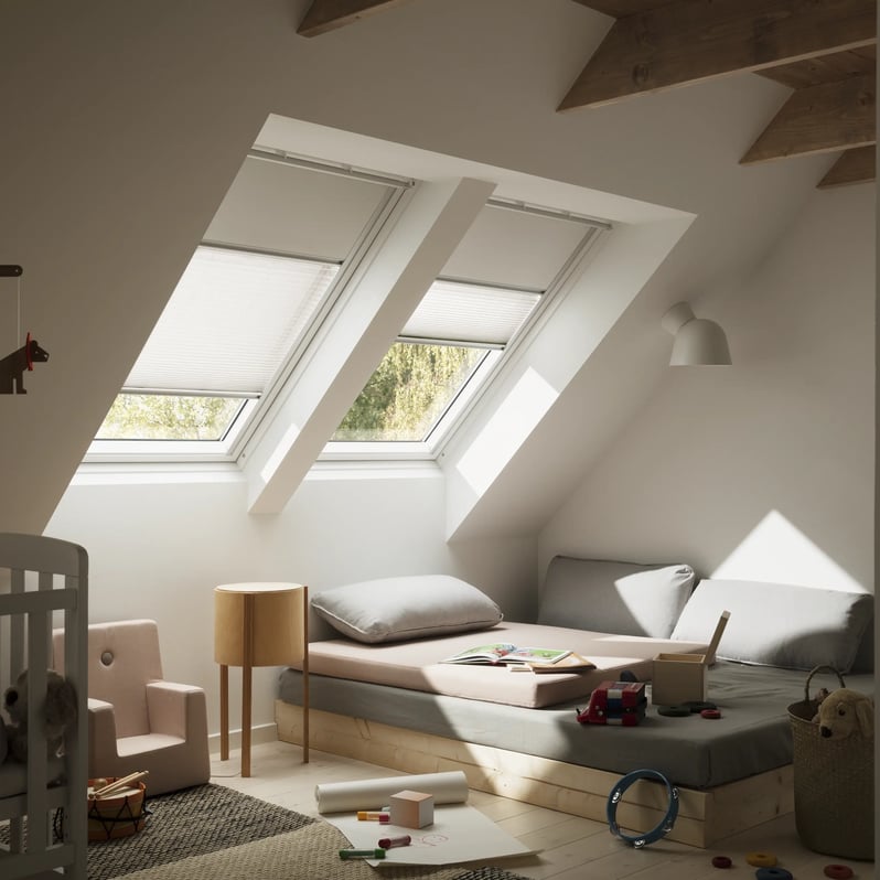 Attic kids room with sloped ceiling and VELUX roof windows, cozy play area.