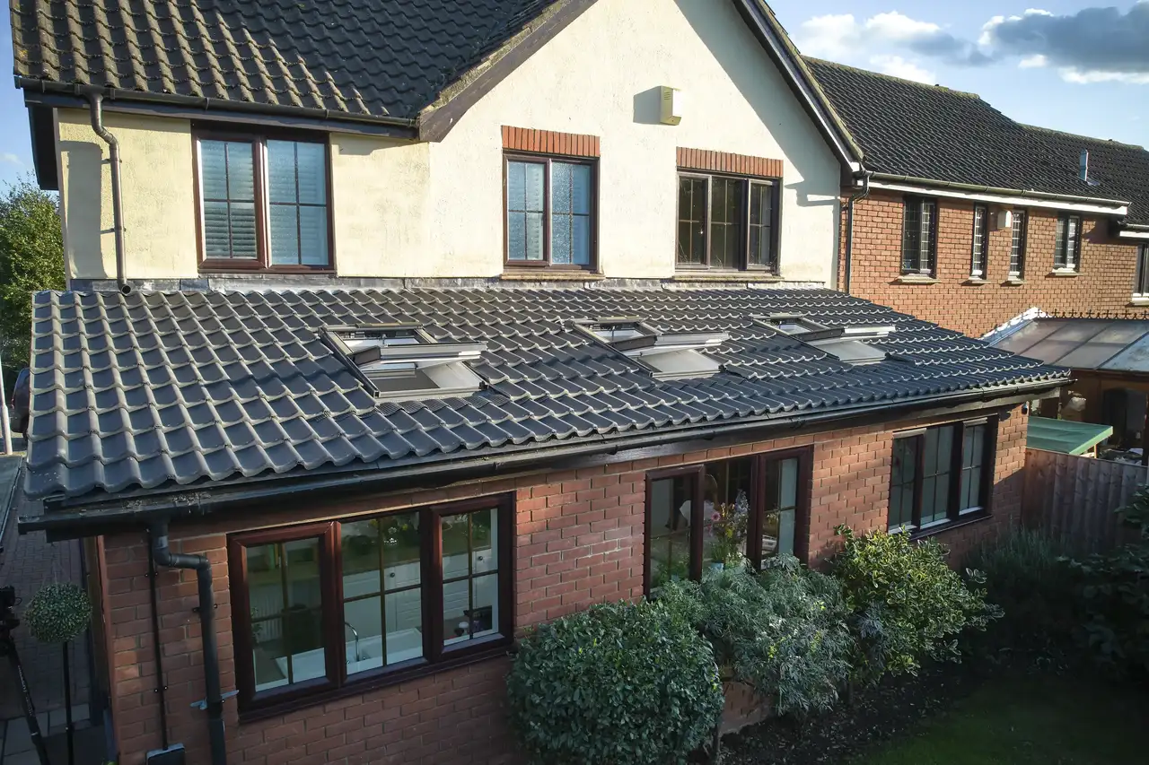 Modern house with tiled roof and VELUX roof windows, surrounded by garden.