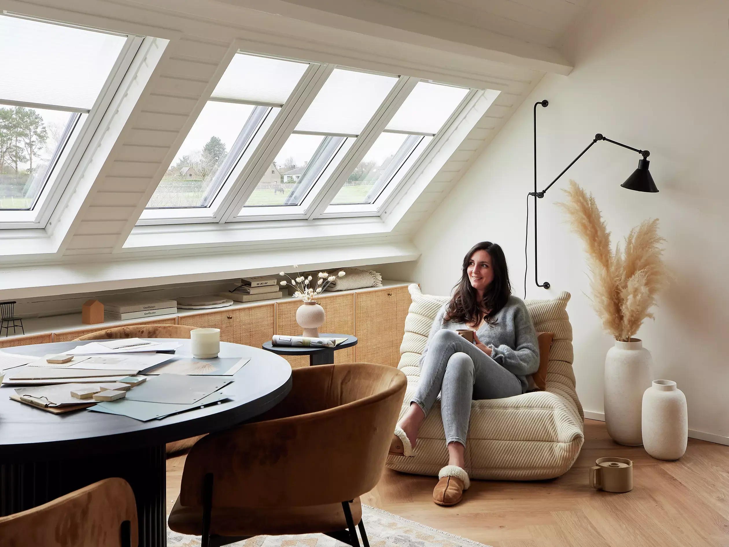 Espace de lecture serein dans le comble avec lumière naturelle provenant des fenêtres de toit VELUX, fauteuil confortable et décoration.