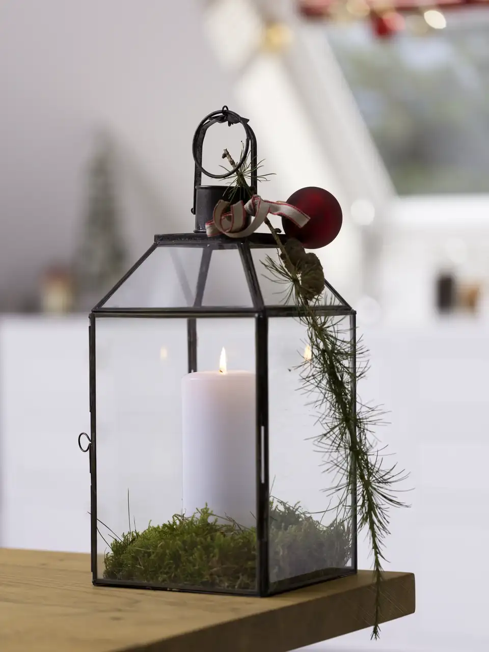 Lanterna in vetro con candela e dettagli naturali accanto a una finestra per tetti VELUX.