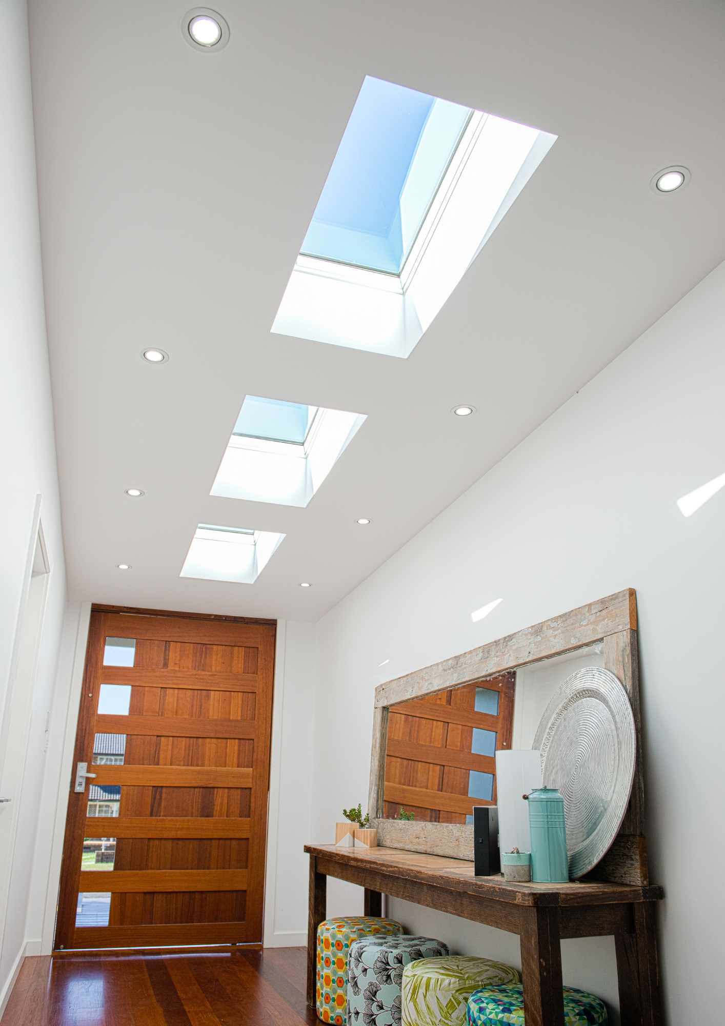Hallway with skylights and wooden door, bright and airy.