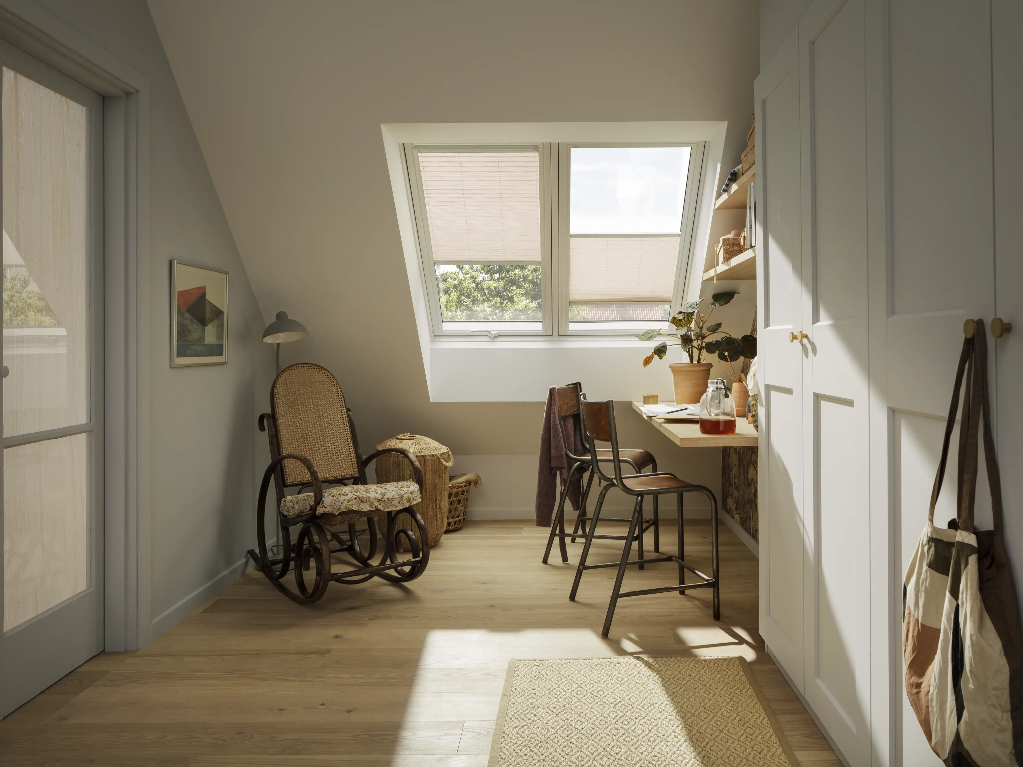 Home office in mansarda con scrivania sotto due finestre per tetti VELUX dotate di tende.