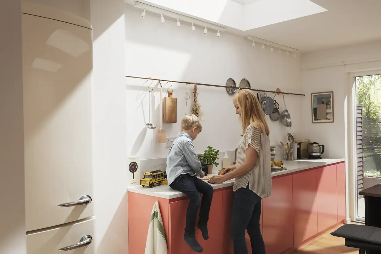 Cuisine lumineuse avec fenêtres de toit VELUX, meubles roses et ambiance chaleureuse dans un style Dopamine decor 