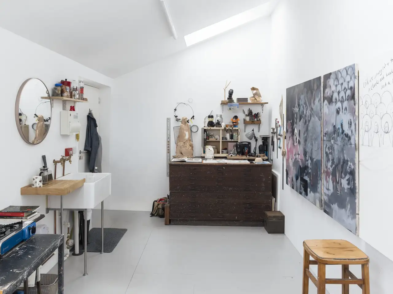 Coin créatif sous combles avec matériel artistique, grande œuvre murale et fenêtre de toit. 
