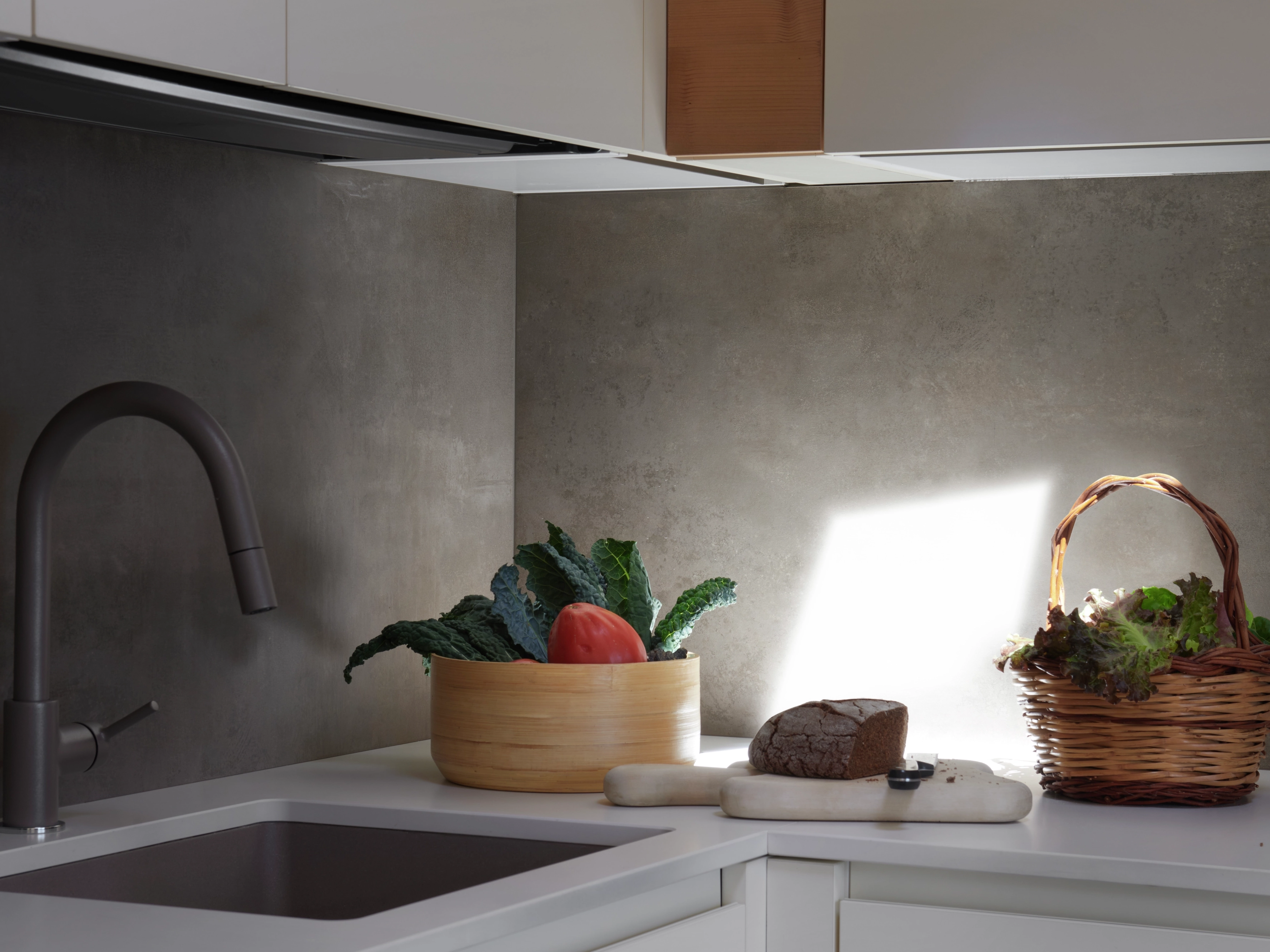 Angolo cucina moderna con luce naturale e prodotti freschi sul piano di lavoro.