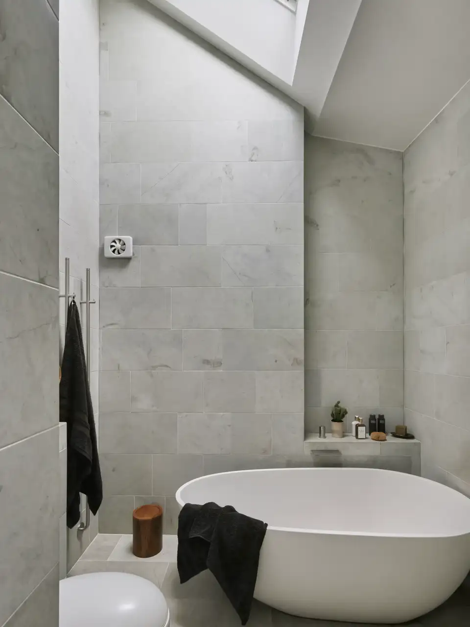 Badkamer met ligbad en VELUX dakraam, marmeren tegels.