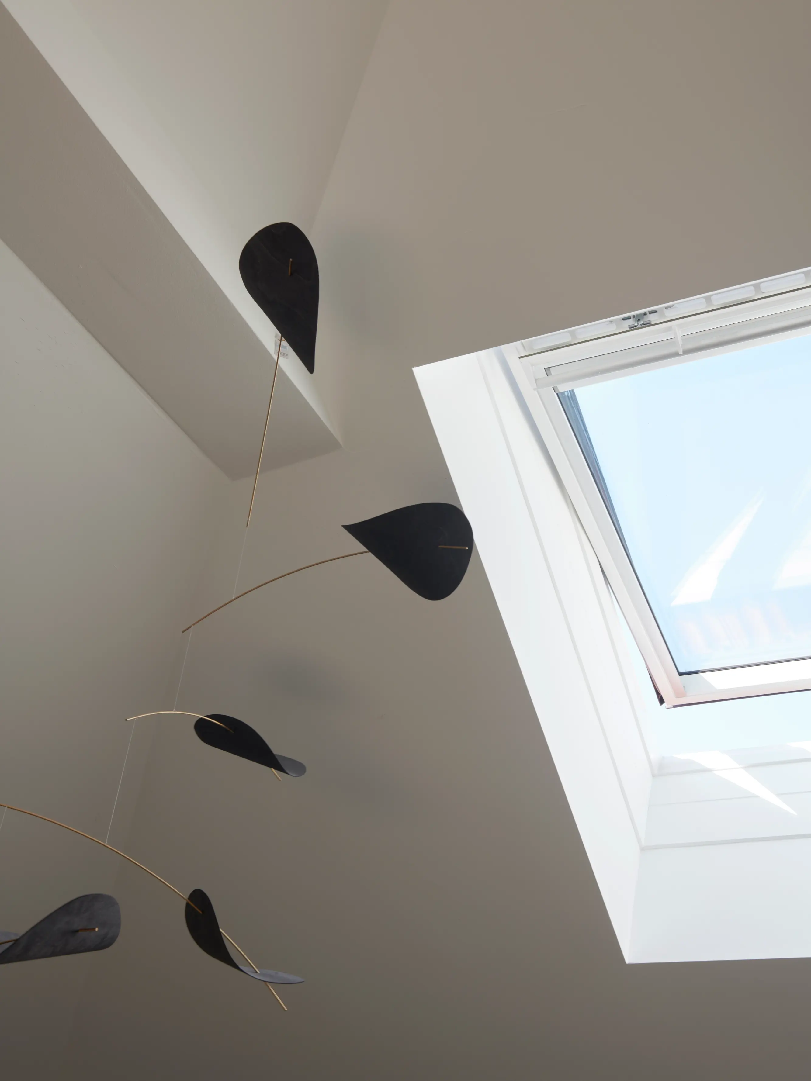 Chambre moderne avec sculpture mobile et lumière naturelle provenant d'une fenêtre de toit VELUX.