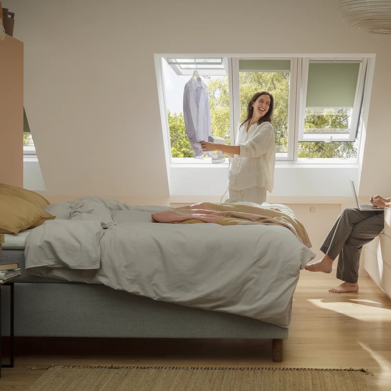 Attic bedroom with sloped ceiling and VELUX roof windows, cozy decor.
