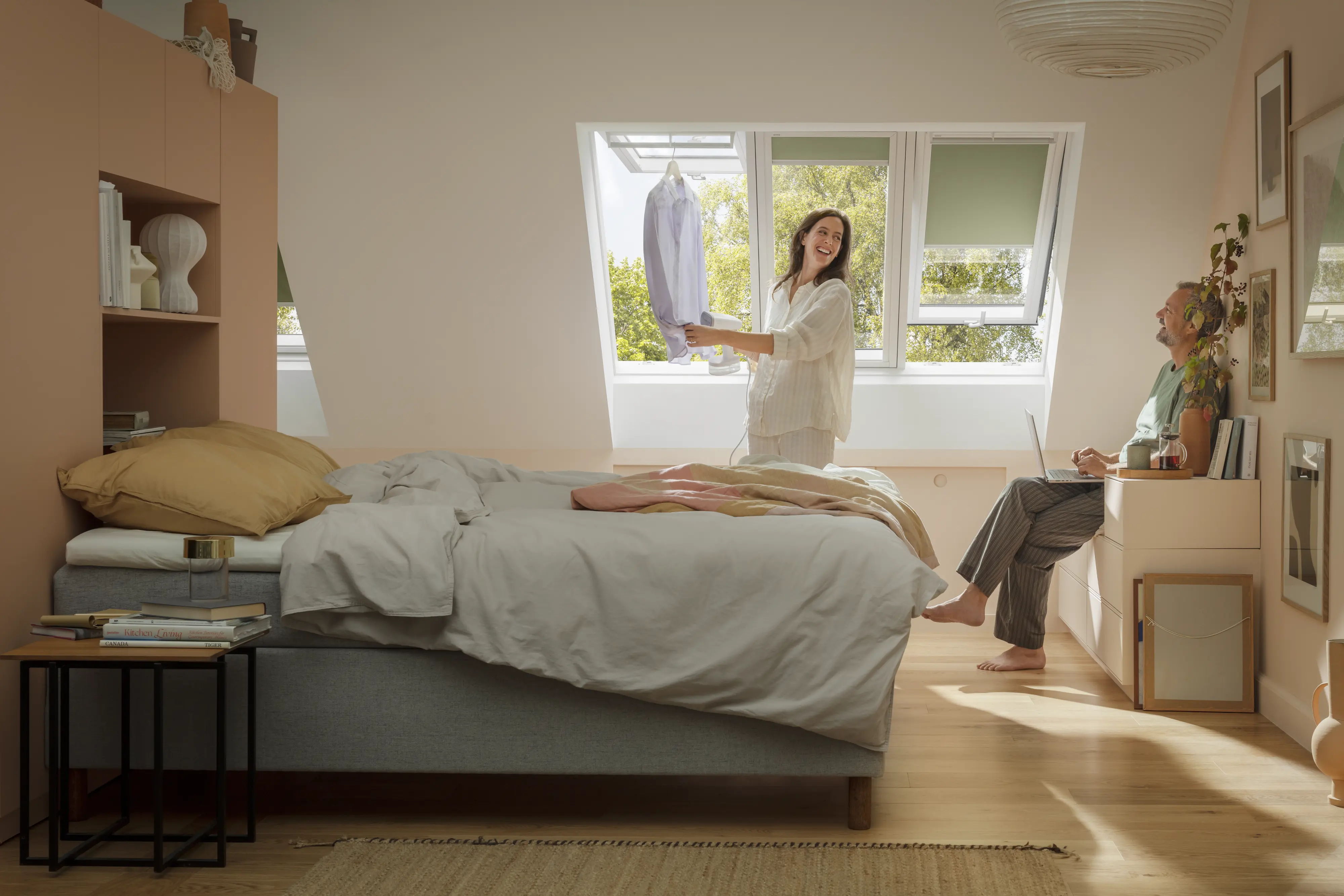 Attic bedroom with sloped ceiling and VELUX roof windows, cozy decor.