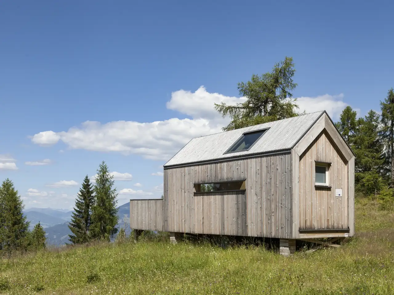 Piccola casa in montagna in legno con tetto spiovente e finestra per tetti VELUX.
