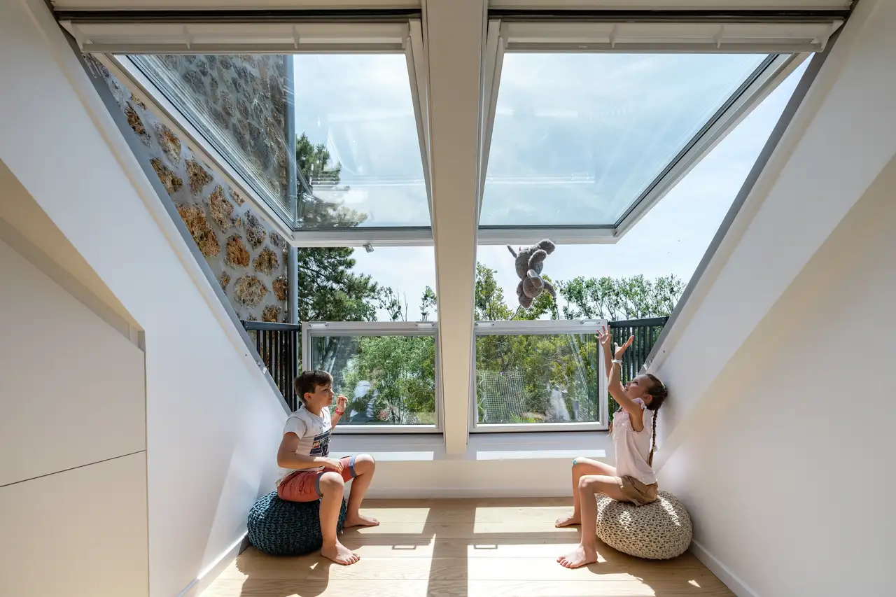 Speelkamer op zolder met een VELUX dakvenster: kinderen spelen met speelgoed. 
