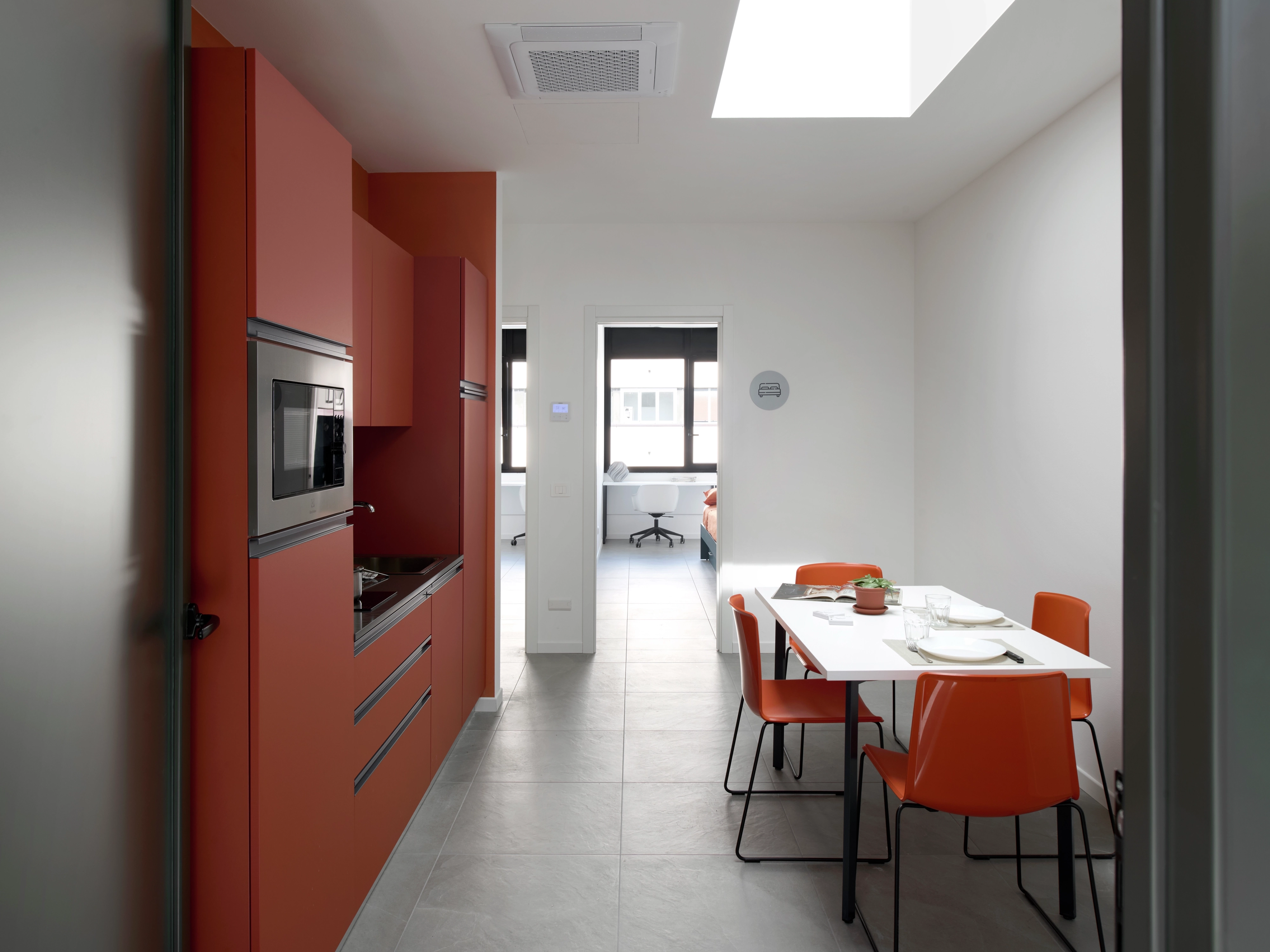 Cucina con tavolo da pranzo illuminata da una finestra per tetti piani VELUX. 