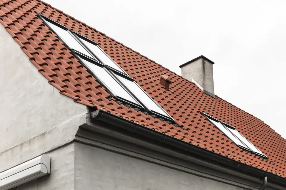 maison avec toit à deux pans en tuiles rouges, cheminée et fenêtres de toit VELUX