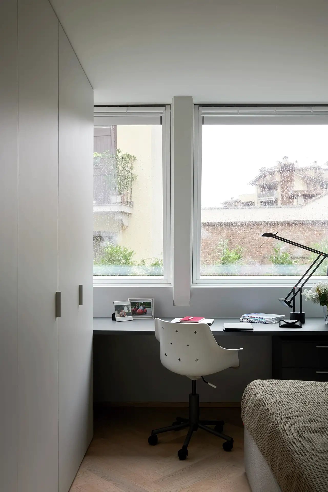 Dormitorio en el ático con cama, armario y escritorio situados debajo de dos ventanas de tejado VELUX.