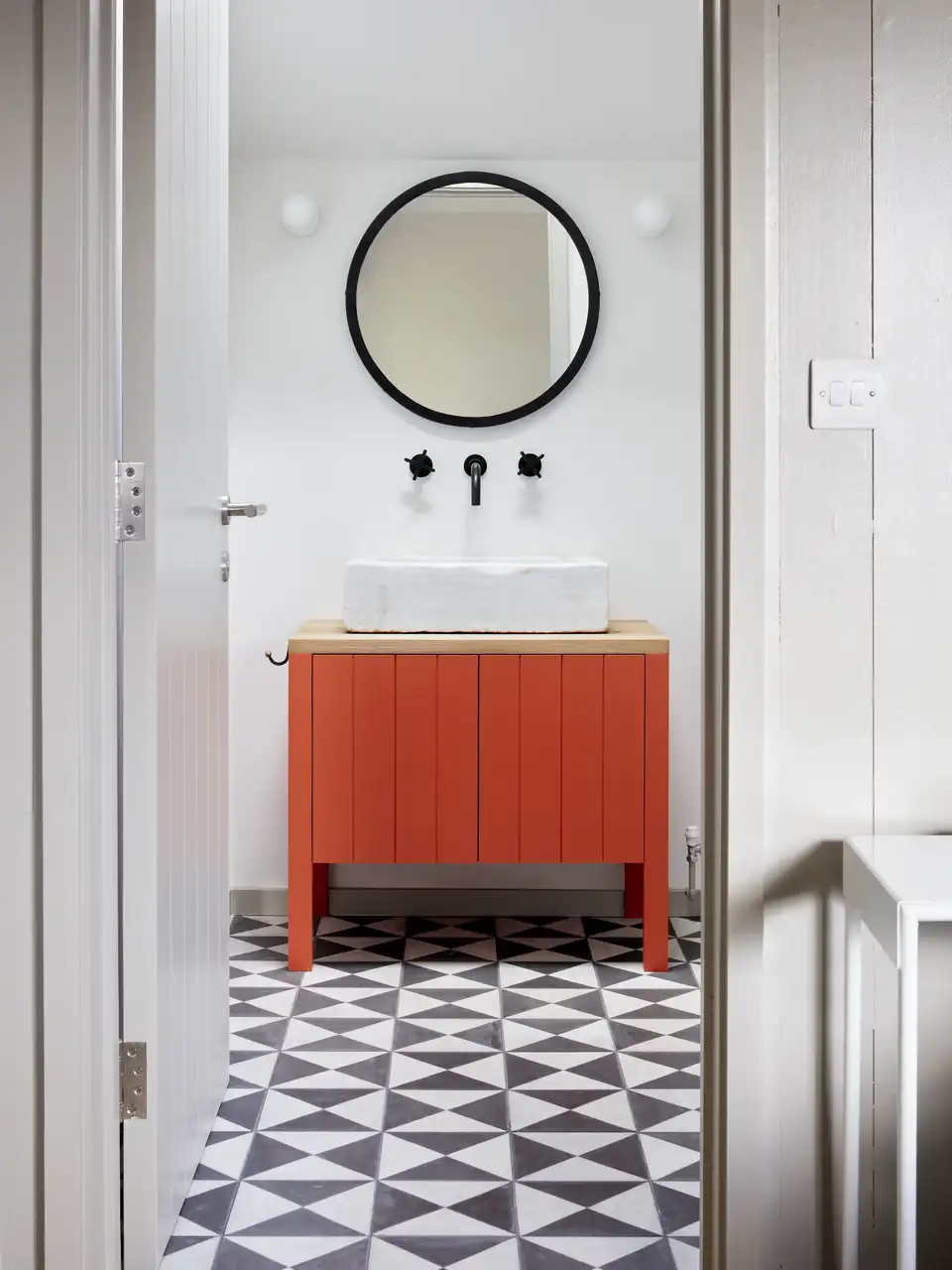 Salle de bain moderne avec meuble vasque rouge et fenêtre de toit. 