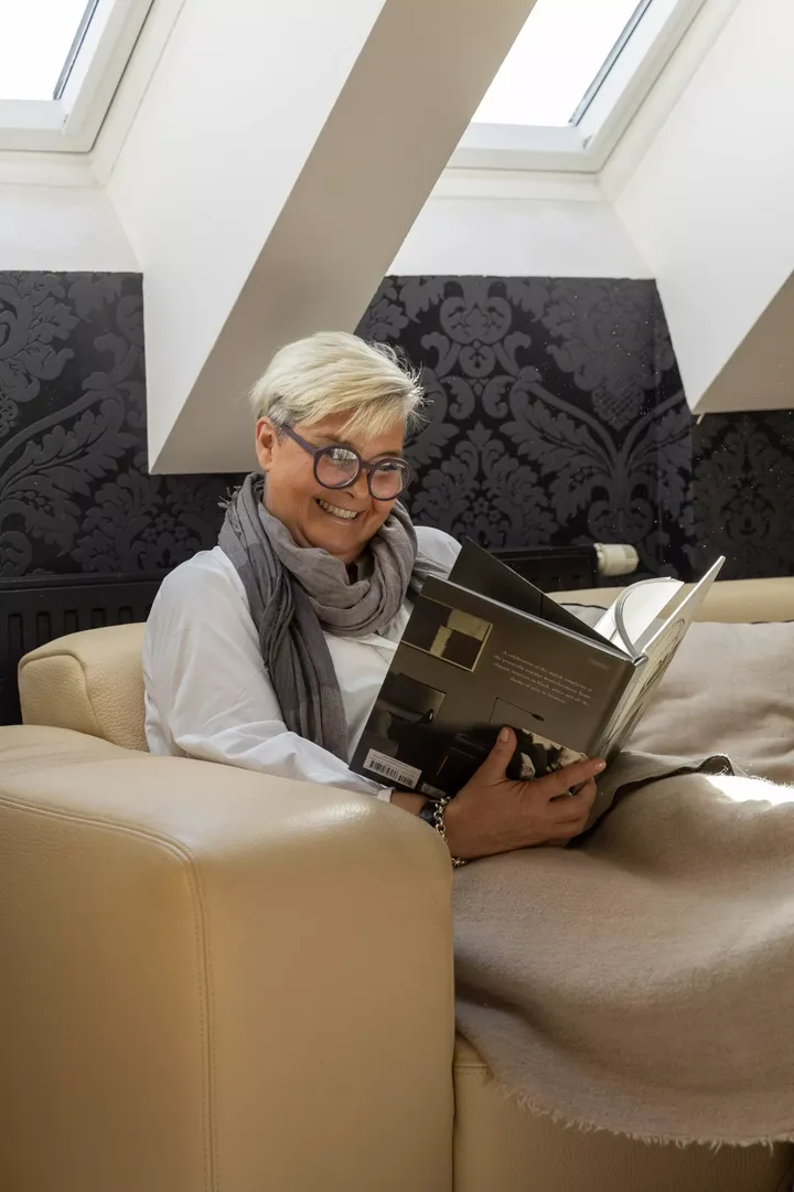 Gemütliche Wohnzimmerecke mit einem VELUX Dachflächenfenster, cremefarbenem Sofa und einer lesenden Person.