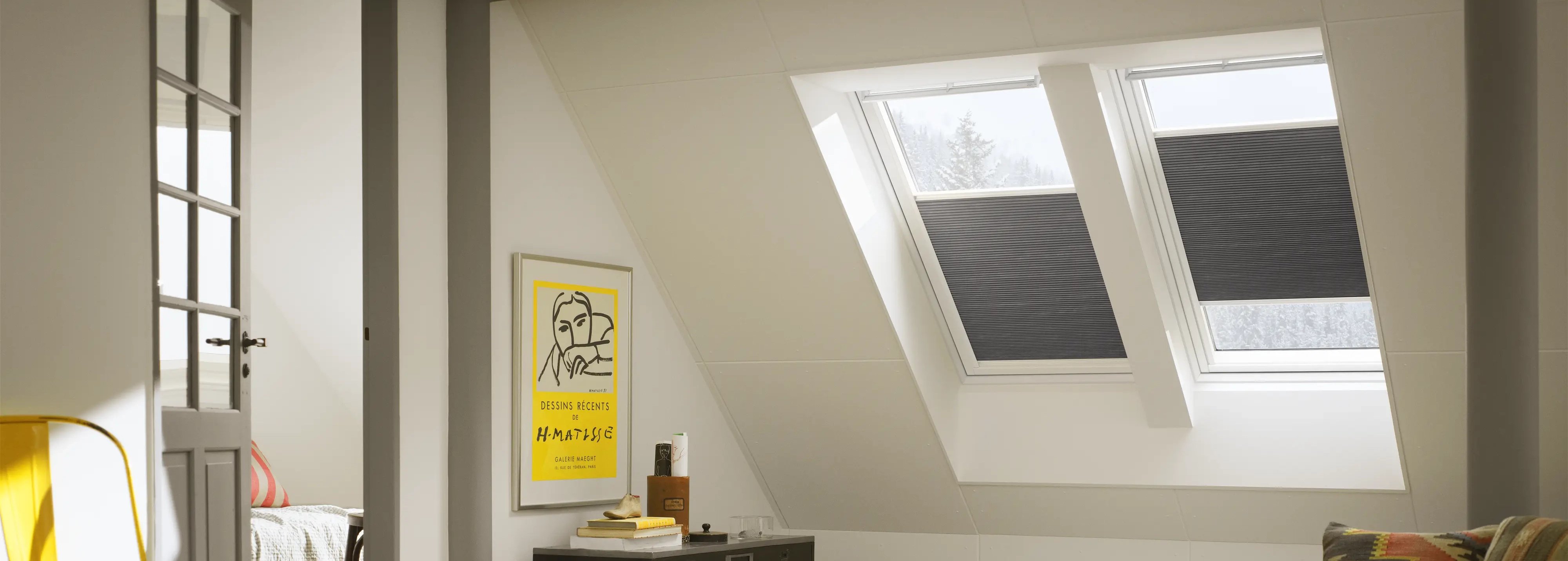 Attic living space with sloped ceiling and VELUX roof windows, cozy decor.
