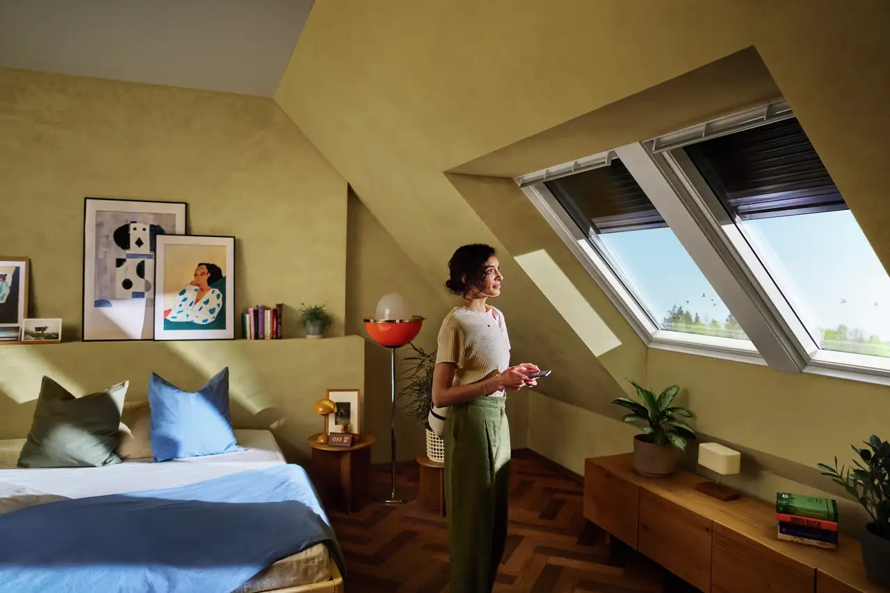 Femme utilisant le système VELUX App Control pour commander les fenêtres de toit et leurs volets depuis son smartphone