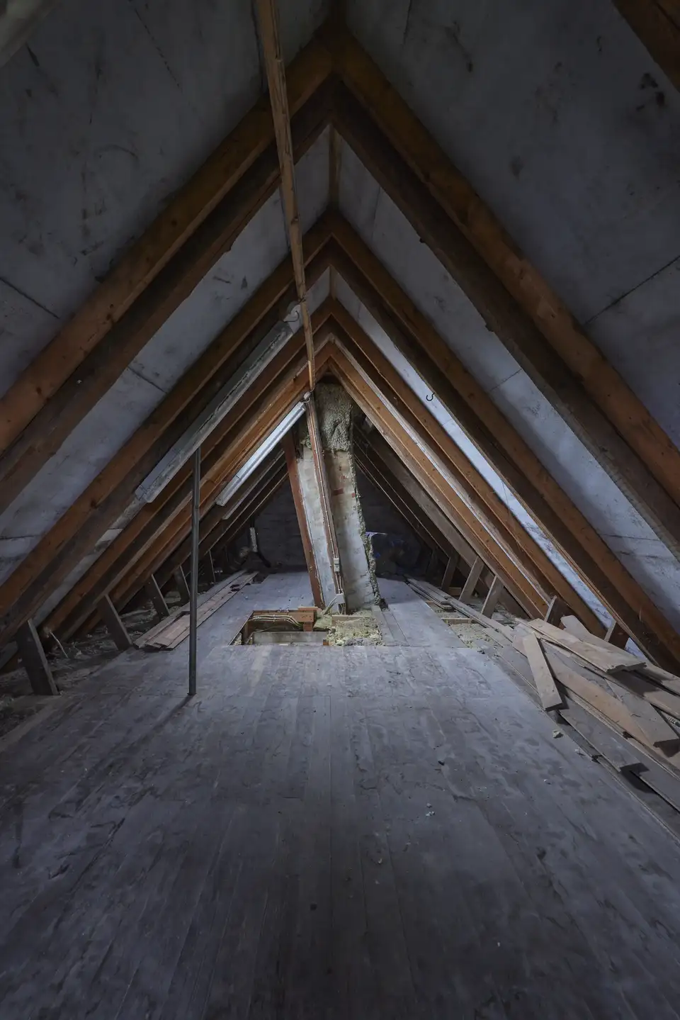 Staré, tmavé podkrovie s odhalenými trámami a holou podlahou, ukazujúce potenciál pre renováciu. | VELUX