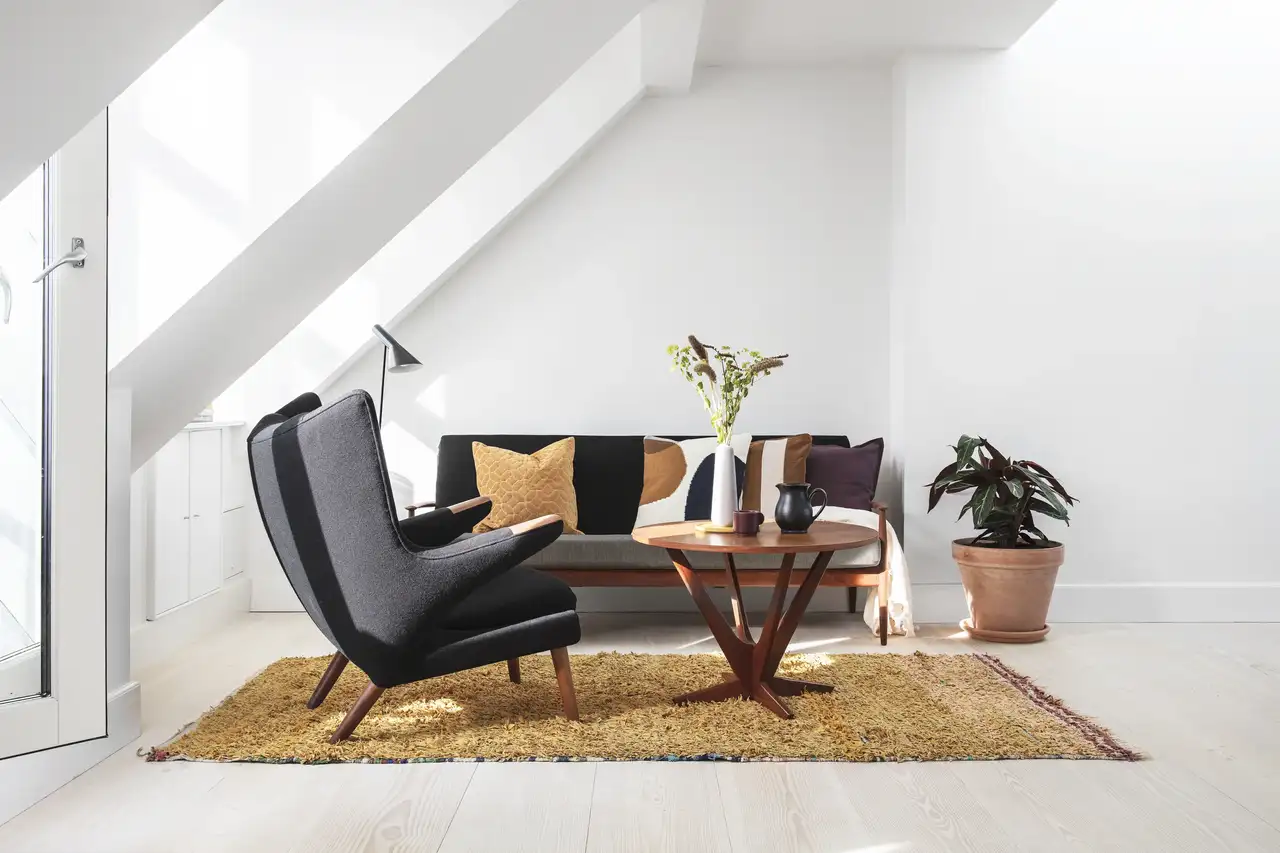 Zolderwoonkamer met schuine plafonds en VELUX dakraam, moderne inrichting.