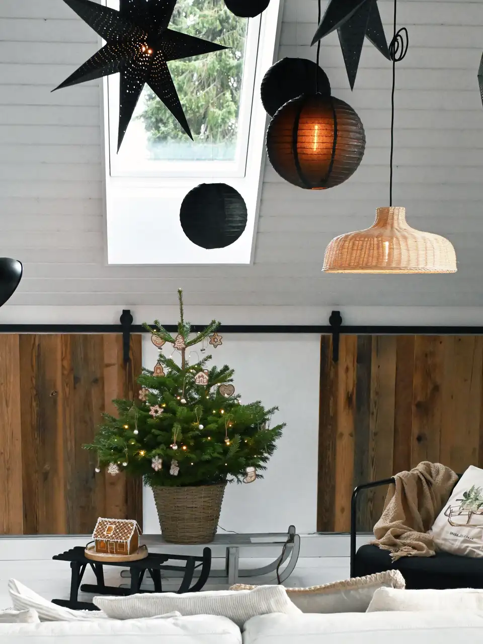 Salon nordique contemporain avec sapin de Noël en pot, décorations minimalistes et fenêtre de toit VELUX.