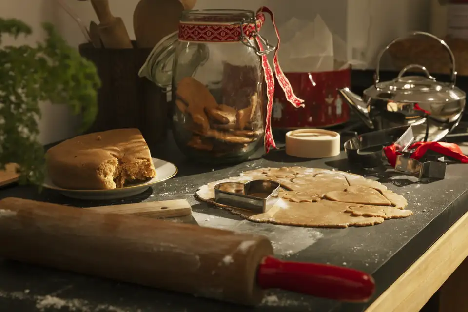 Impasto e biscotti allo zenzero su un piano da lavoro e un contenitore trasparente con fiocco rosso