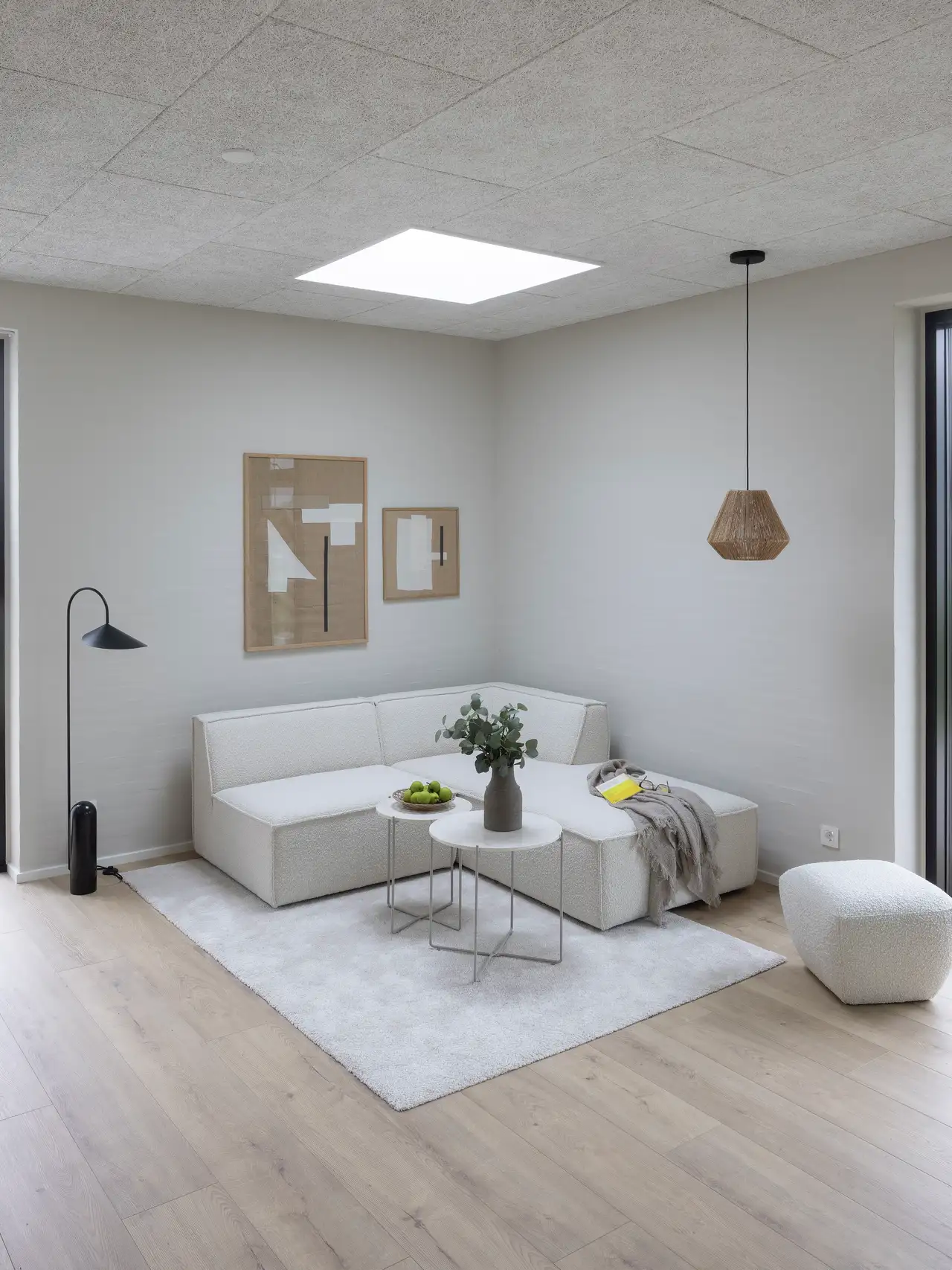 Salon au design épuré avec mobilier blanc et canapé d’angle sous une fenêtre pour toit plat.