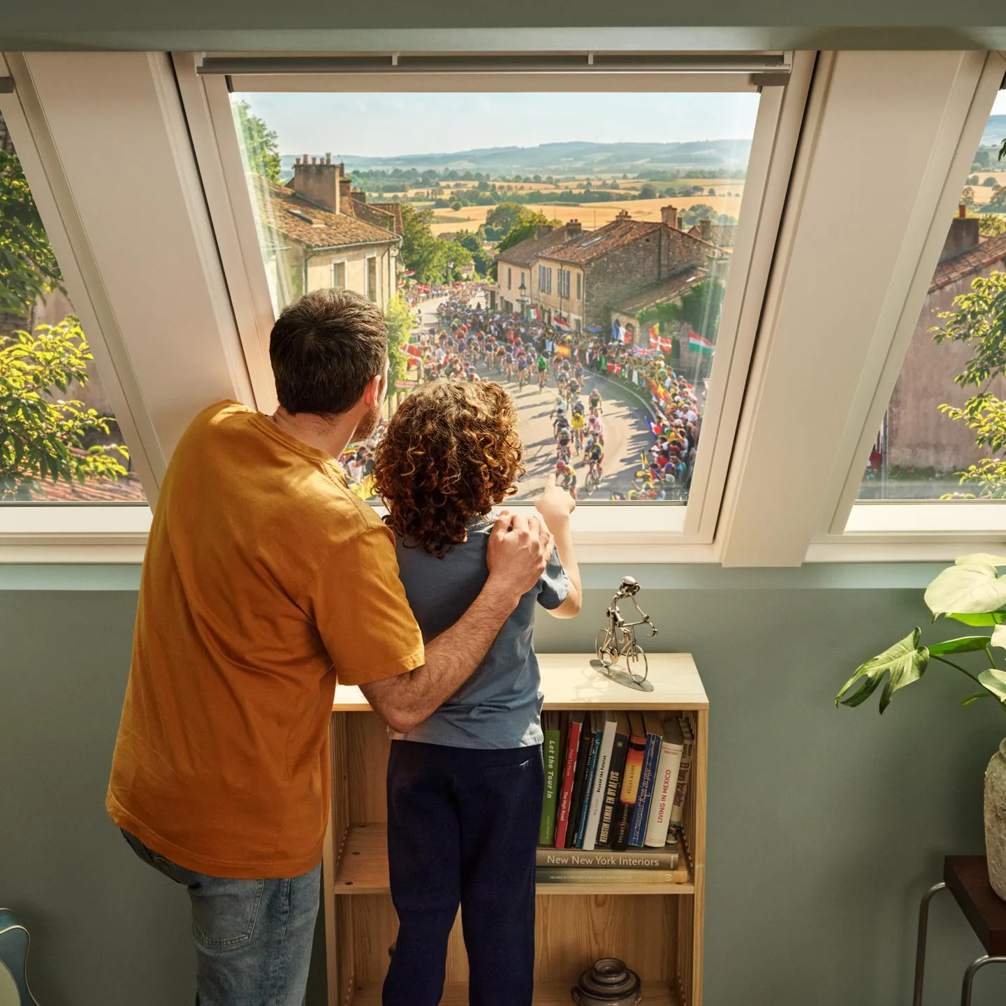 Un père et son fils regardant le Tour de France par une fenêtre de toit VELUX 