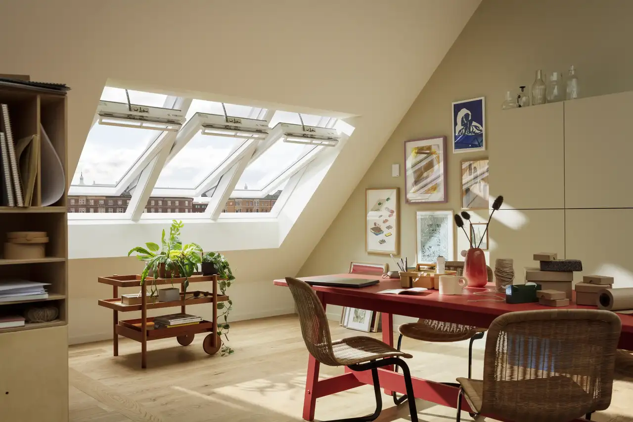 Espace de travail aménagé dans une mansarde avec fenêtres de toit VELUX ouvertes et mobilier coloré.