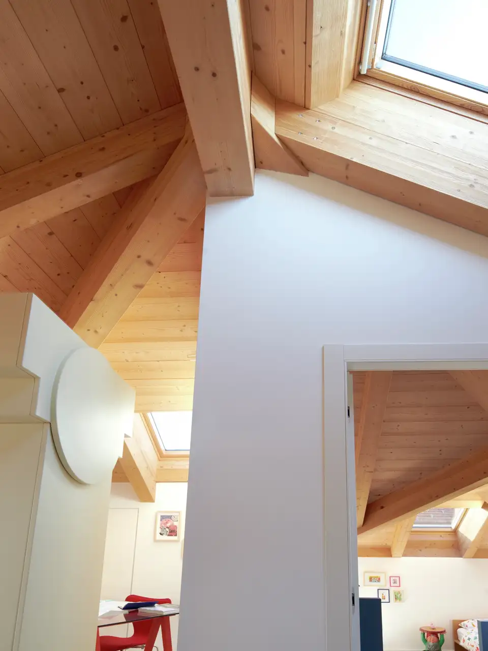 Vivienda con tejados abuhardillados con techo de madera y ventana de tejado. 