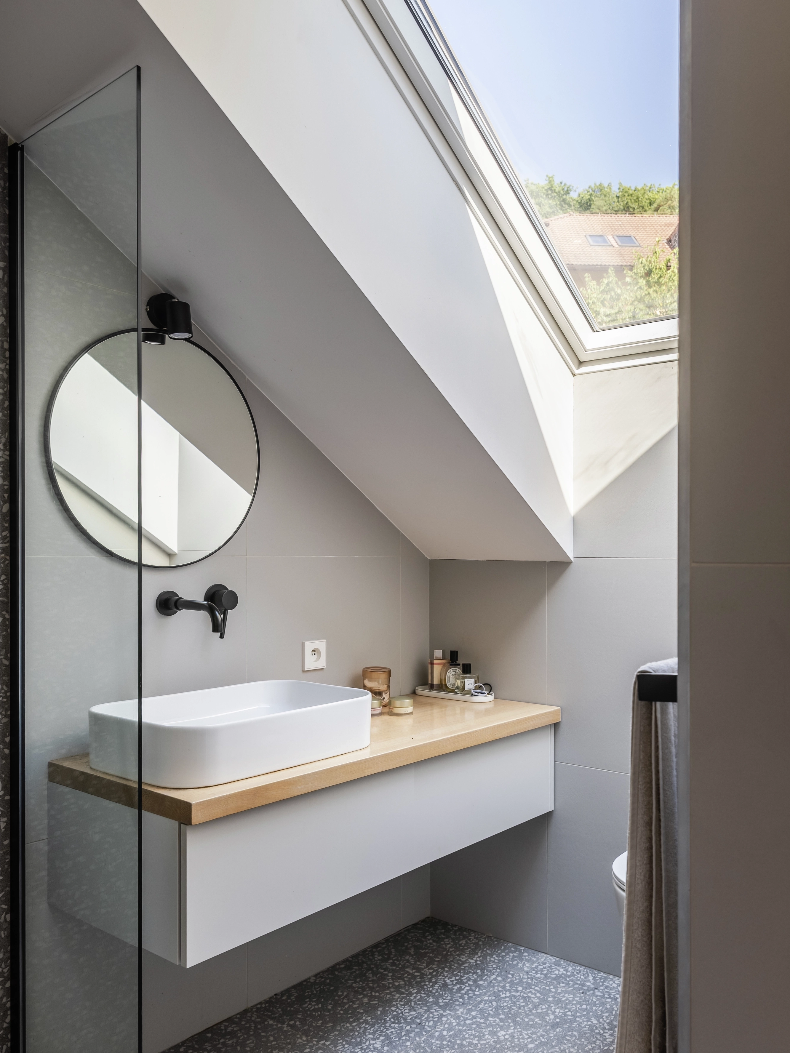 Attic bathroom with sloped ceiling and VELUX roof window.